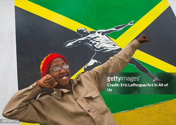 Rastafari girl called kizzy in front of a jamaica flag with hussein bolt mural, oromo, shashamane, Ethiopia on March 23, 2016 in Shashamane, Ethiopia.