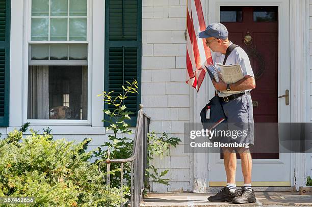 United States Postal Service mailman Mike Micali looks at a barking dog in a window while making deliveries in Flemington, New Jersey, U.S., on...