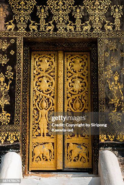 the laotian golden gilded black lacquer art technique and wood carving at the door inside wat xieng thong - wat imagens e fotografias de stock