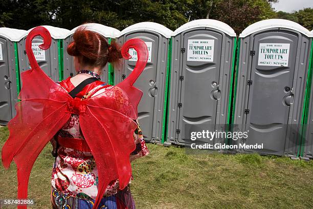 Young woman wearing fairy wings waits in the queue for the portable toilets at Camp Bestival, which takes place at Lulworth Castle in Dorset. This is...