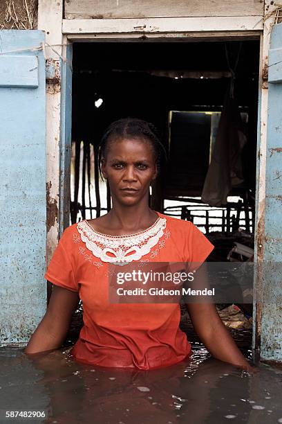 Adlene Pierre, aged 35, faces the camera in front of one of the windows of her flooded house in Savanne Desole on the outskirts of the city of...