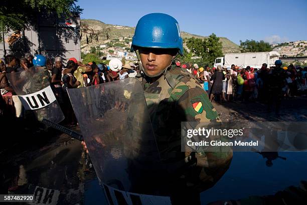 Guatemalan soldiers with riot gear who are part of MINUSTAH provide security as hundreds of hungry people queue for food relief in the flooded city...