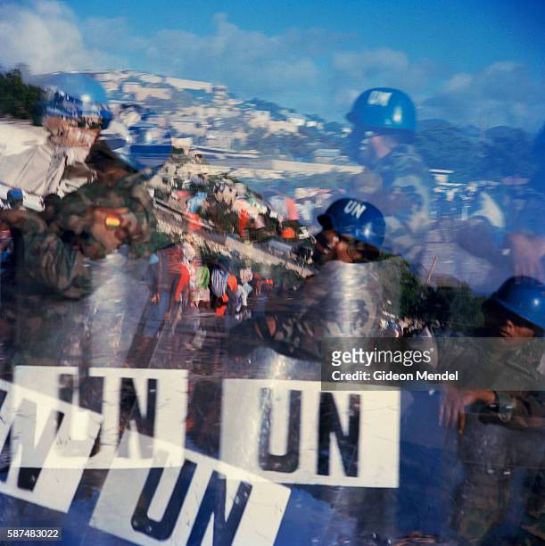 Photograph of UN soldiers guarding a food distribution for flood victims is strangely double exposed due to damage done to the camera by floodwater....