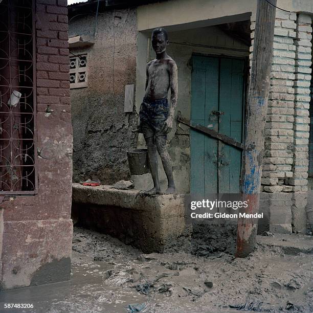 Boy pauses for a moment as works on cleaning the mud out of his flooded home in the city of Gonaives, two weeks after it was flooded during...