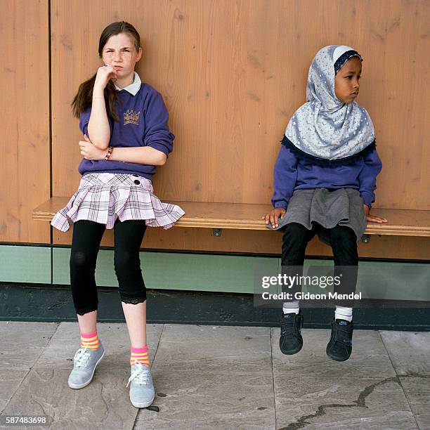 Two girls from different ethnic backgrounds pause for a moment during playtime at Kingsmead Primary School, which serves children who live on the...