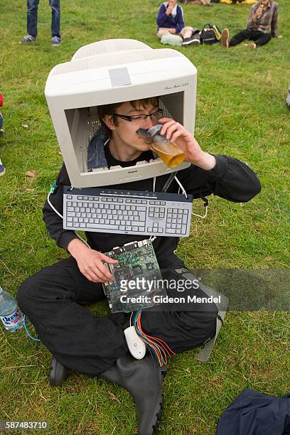 Young man attempts to dring his pint of beer through his broken computer screen as he participates in the fancy dress contest at the Standon Calling...