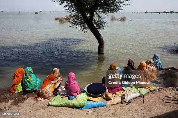 Group of women watch the floodwaters slowly rise on the outskirts of Manghal Khan Brohi village. Shortly after the walls of Manchar Lake were...