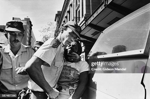 South African police officers aggressively arrest Moses Mayekiso, a prominent trade union leader, during a protest march in Johannesburg, South...