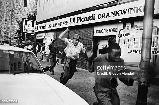 South African police officer charges after a United Democratic Front demonstrator with a sjambok whip during a Front demonstration in Johannesburg,...