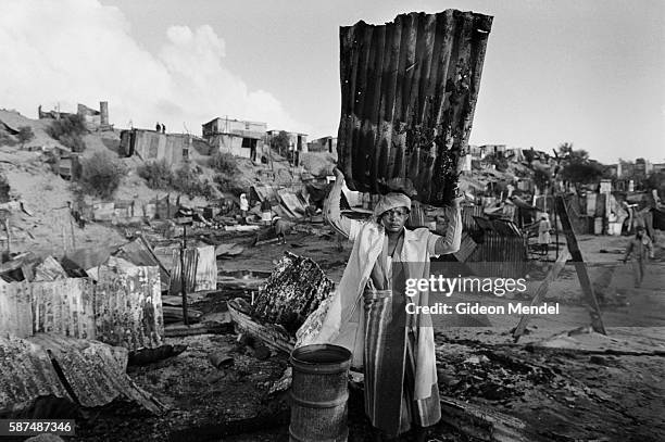 Woman holds a piece of corrugated steel from her burned-out shack in the KTC Squatter Camp in Cape Town, South Africa. The squatter camp had been...
