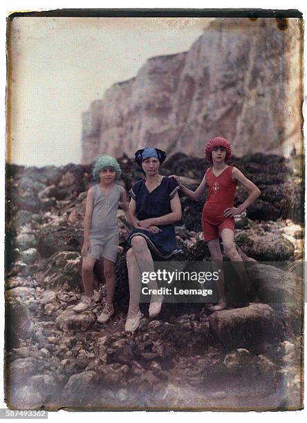 Portrait of a family, a mother and her two daughters from the Parisian bourgeoisie posing on a rock on the beach, probably near Etretat, Normandy -...