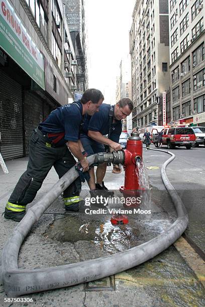 After responding to a call in Chelsea fire fighters pack up their gear, disconnect the fire hose and turn off the fire hydrant.