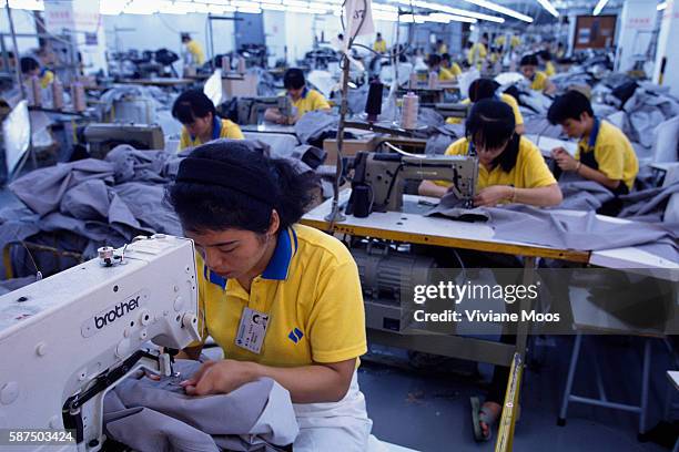 Workers at a textile factory work on sewing machines, making jeans and jackets for big label clients.