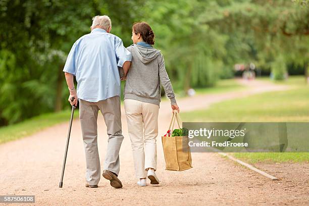 cuidador ayudando a senior mujer-hombre con el centro comercial - woman carrying tote bag fotografías e imágenes de stock