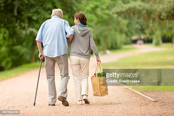 caregiver – woman helping senior man with shopping - senior adult stock pictures, royalty-free photos & images