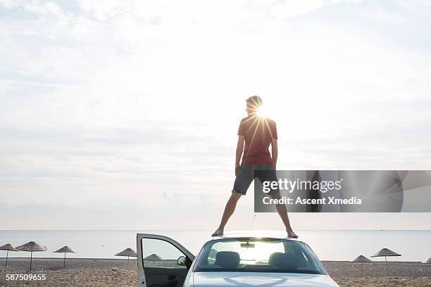 young man stands on top of car, above sea, beach - oberer teil stock-fotos und bilder