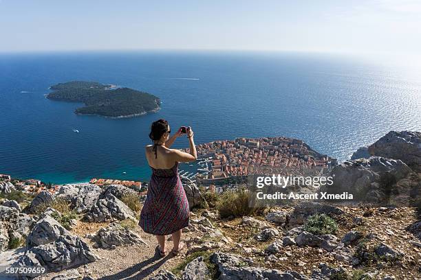 woman takes picture of fortified town, sea - dubrovnik stockfoto's en -beelden