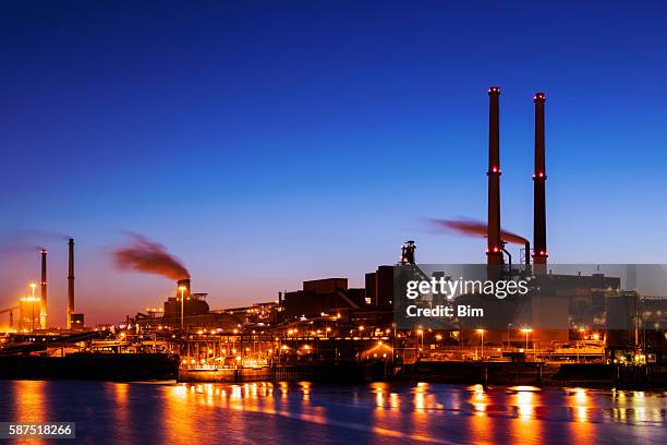 beleuchtete industrielle anlage am fluss bei nacht, amsterdam, niederlande - steel mill stock-fotos und bilder