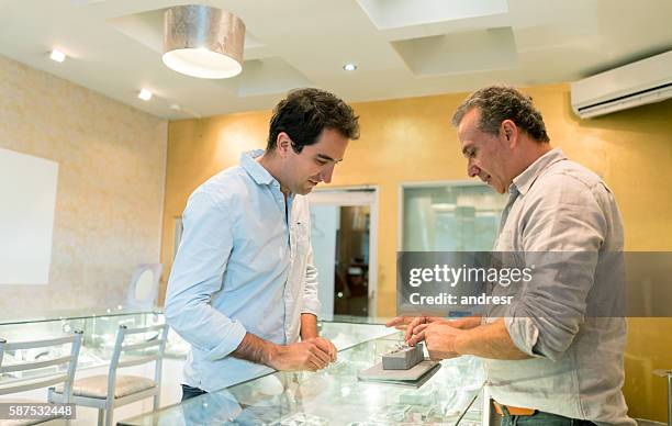 hombre comprando un anillo de compromiso - jeweller fotografías e imágenes de stock