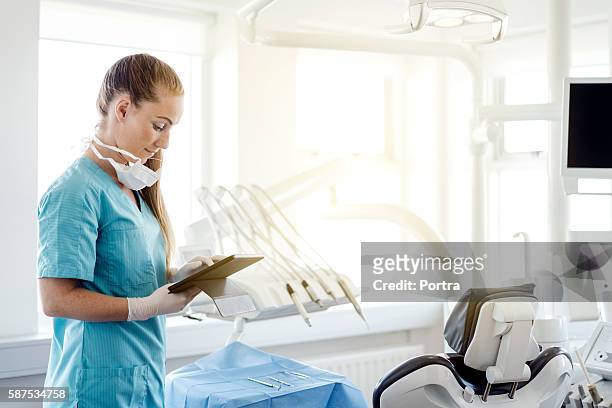 dentist using digital tablet by chair in clinic - clinic imagens e fotografias de stock