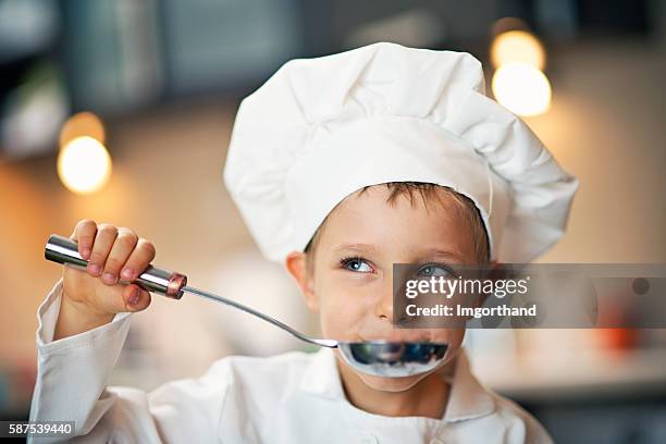 little boy chef tasting soup. - kokskostuum stockfoto's en -beelden