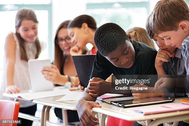 school kids in class using a digital tablet - gemengde afkomst stockfoto's en -beelden