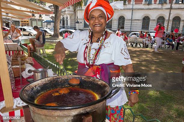 Saint George day pageantry and procession. Sonia, a big Bayana woman from Bahia in her traditional dress preparing her traditional deep fried acaraje...