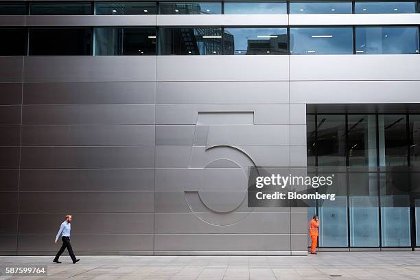 Pedestrian walks past No. 5 Broadgate, an office complex to be occupied by UBS AG, as construction work nears completion in London, U.K., on Tuesday,...