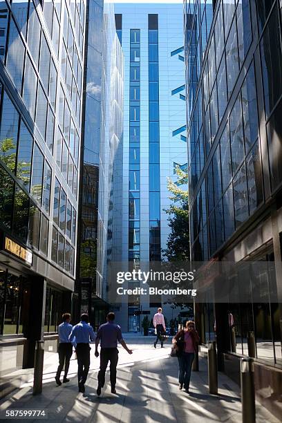 Pedestrians walk towards No. 5 Broadgate, an office complex to be occupied by UBS AG, center, as construction work nears completion in London, U.K.,...