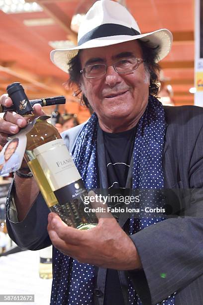 Al Bano Blake signs autographs on his bottles of wine as he attends a meet and greet with the public on August 8, 2016 in Marina di Gioisa Jonica,...