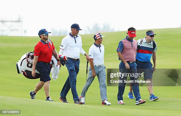 Matt Kuchar, Rickie Fowler and Bubba Watson of the United States walk down a fairway with their caddies during a practice round on Day 4 of the Rio...