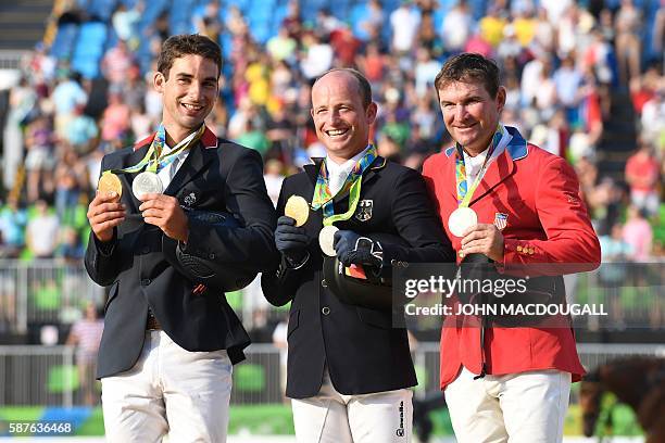 France's Astier Nicolas, Germany's Michael Jung and USA's Phillip Dutton celebrate on the podium of the Eventing's Jumping of the Equestrian during...