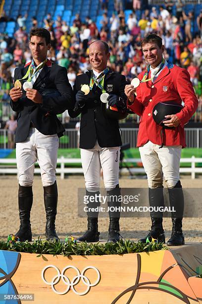 France's Astier Nicolas, Germany's Michael Jung and USA's Phillip Dutton celebrate on the podium of the Eventing's Jumping of the Equestrian during...