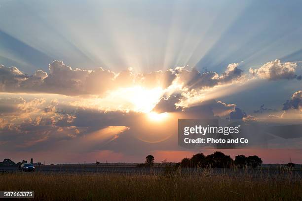 sun shining through cumulus clouds - sole foto e immagini stock