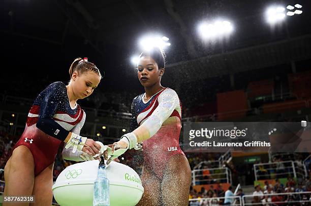 Madison Kocian and Gabrielle Douglas of the United States apply chalk in preparation for competing on the uneven bars during the Artistic Gymnastics...