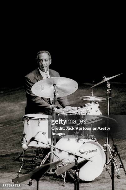 Cigar in his mouth, American comedian and actor Bill Cosby sits behind a drum kit onstage at the 1992 Thelonious Monk International Jazz Drums...
