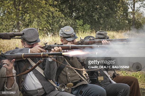 Confederate soldiers using muzzle-loading percussion rifles to fire on Union soldiers. American Civil War, 19th century. Historical reenactment.
