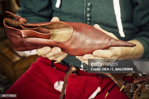 Shoemaker with a women's shoe, 14th century. Historical reenactment.