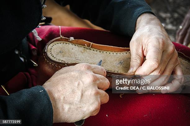 Making a shoe in a shoemaker's workshop, 15th century. Historical reenactment.