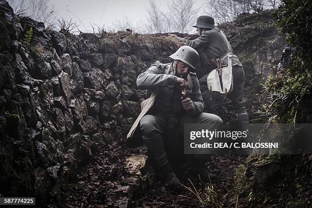 Austro-Hungarian soldier in a trench lighting his pipe while another stands sentry, autumn 1916. First World War, 20th century. Historical...