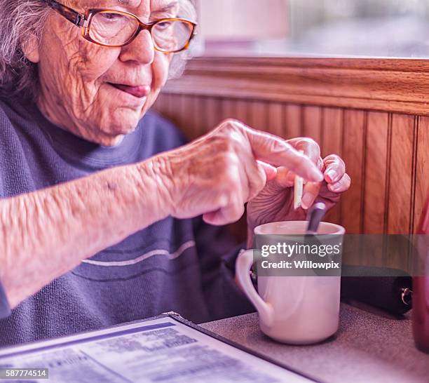elderly woman sticking tongue out concentration funny face - sugary coffee drink stock pictures, royalty-free photos & images
