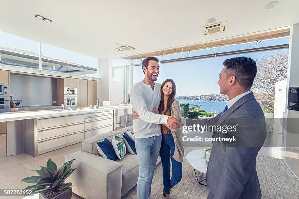 real estate agent with couple in luxury home. - authentic real stockfoto's en -beelden