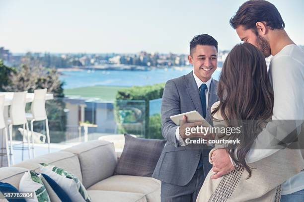 real estate agent with couple in luxury home. - luxury property stock pictures, royalty-free photos & images