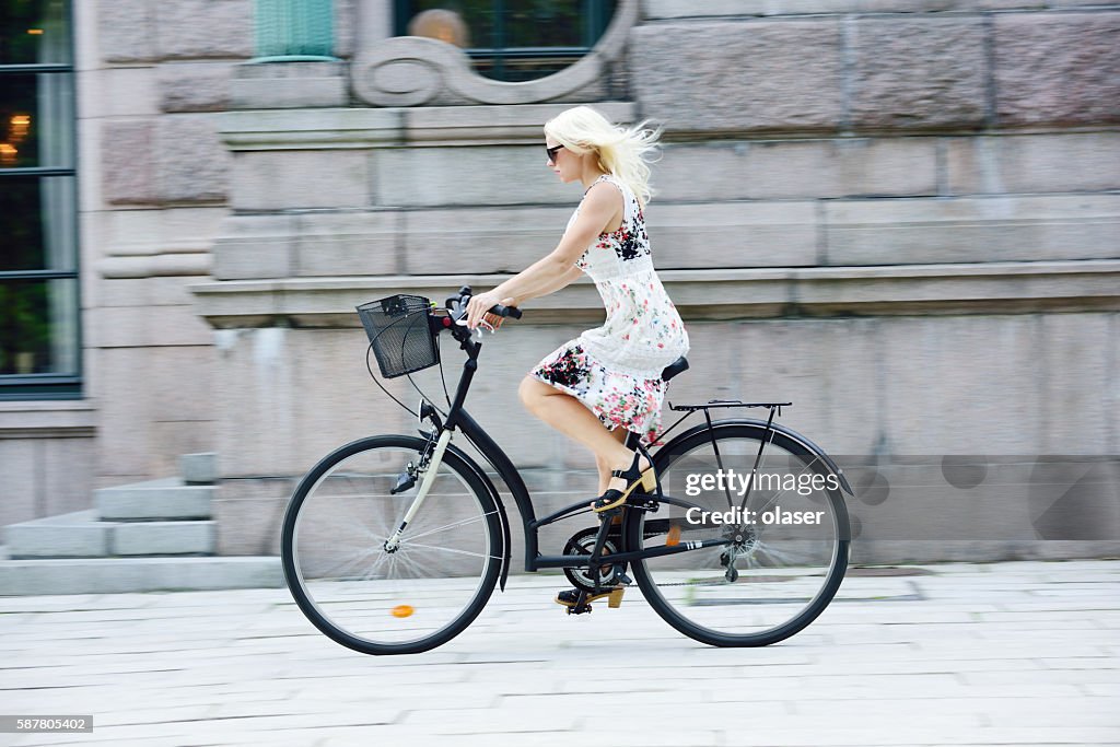 Garota sueca em vestido de verão em bicicleta na cidade