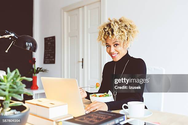 afro american young woman eating lunch at the desk - smart casual lunch stock pictures, royalty-free photos & images