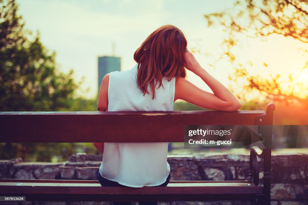 Girl enjoying city view from a bench.