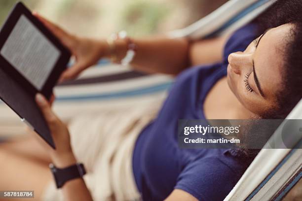 mujer descansando en una hamaca - lector de libros electrónicos fotografías e imágenes de stock