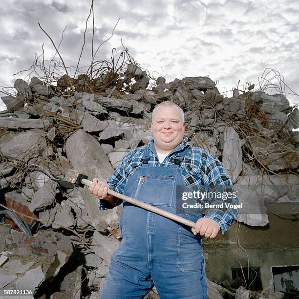 cheerful man with sledgehammer at demolition site - vorschlaghammer stock-fotos und bilder