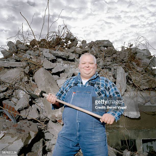 cheerful man with sledgehammer at demolition site - sledge hammer stock pictures, royalty-free photos & images