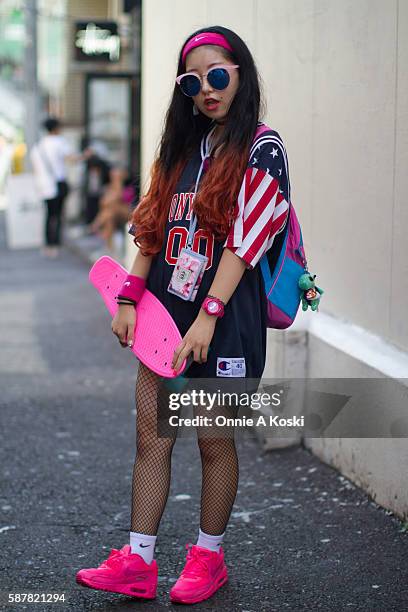 Harajuku, Tokyo Fuuko Kitano, carrying a pink skateboard, is seen on Harajuku St. Wearing a Troll backpack, a red white and blue vintage Champion...